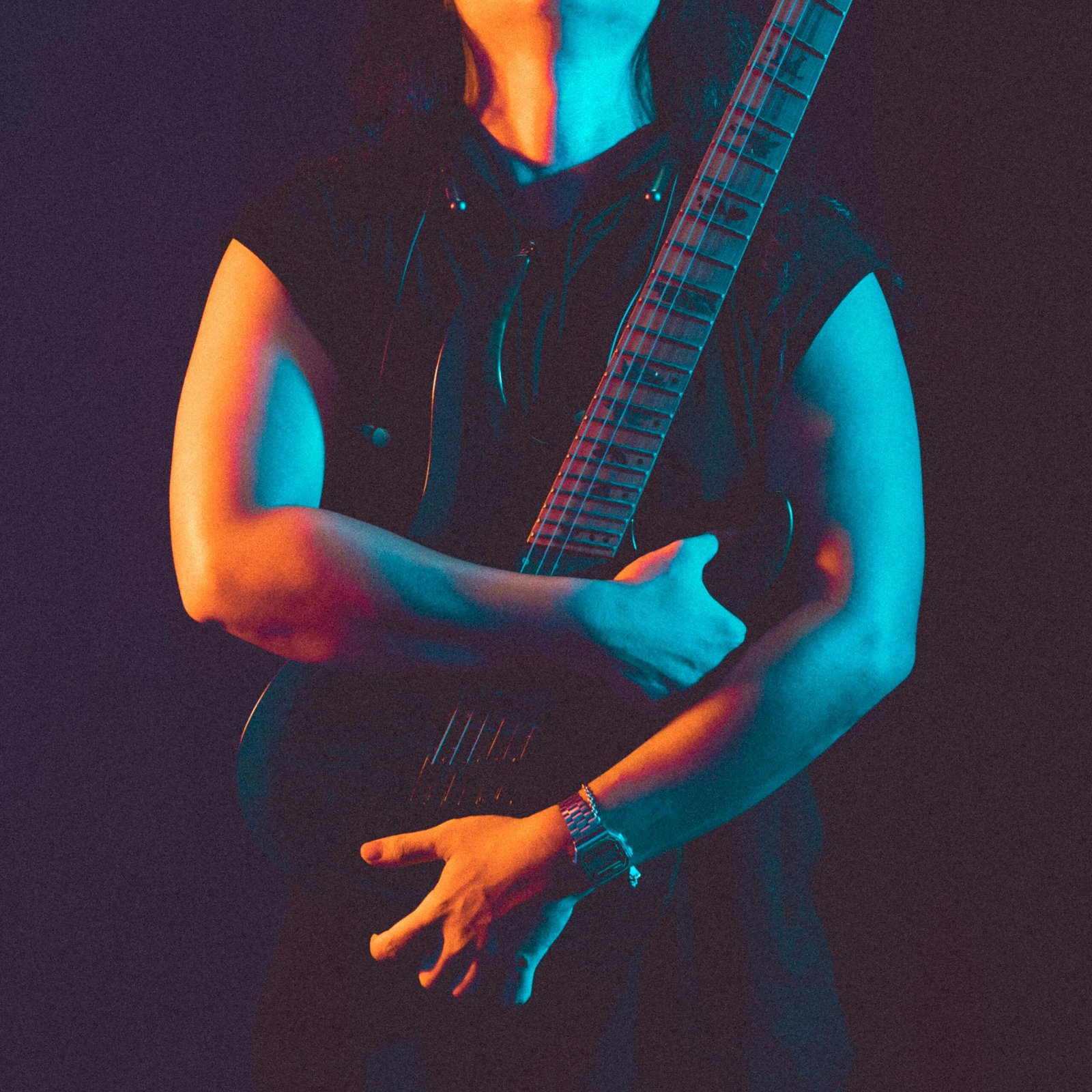 A stylish guitarist poses with an electric guitar under dramatic blue and orange lighting.