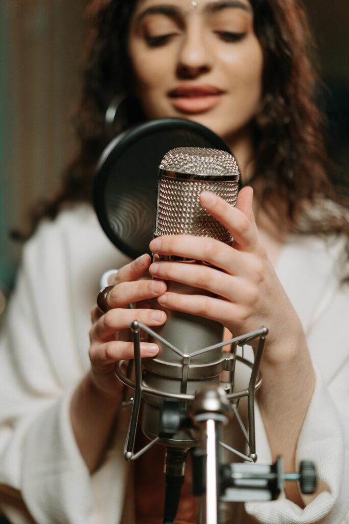 pexels-photo-7090866-7090866 Close-up of a woman singing into a condenser microphone in a recording studio.